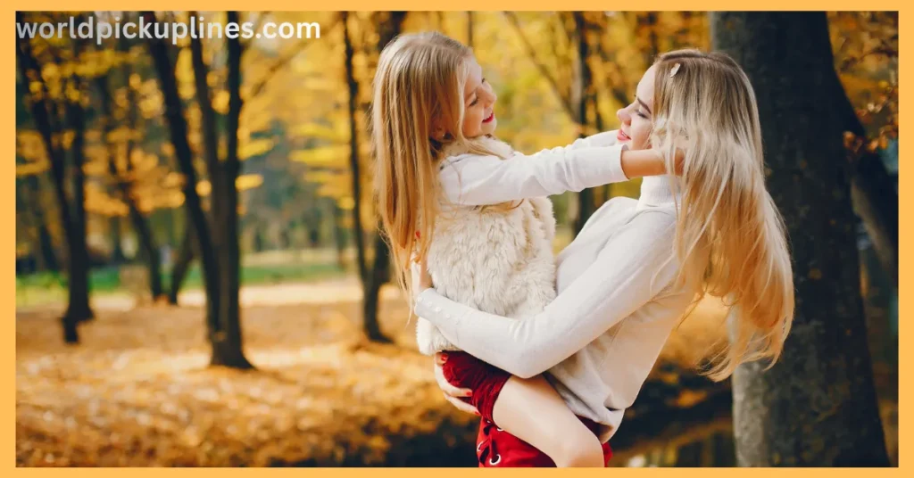 A mother holding her young daughter in her arms outdoors surrounded by autumn trees with yellow foliage.
