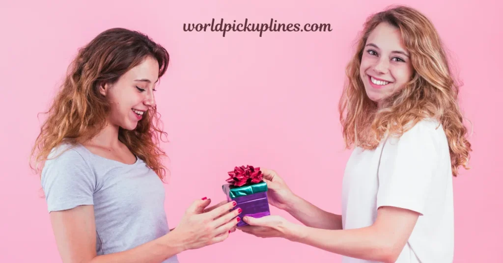 A smiling young woman giving a gift box to another woman against a pink backdrop.