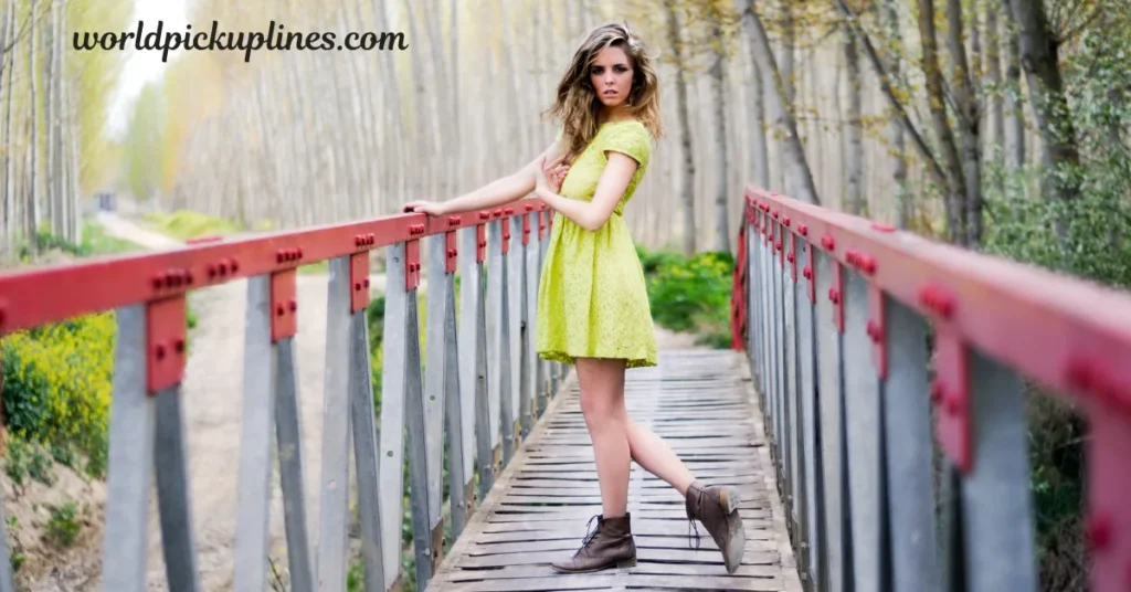 A woman in a lime green dress standing on a wooden bridge with red railings, surrounded by trees.