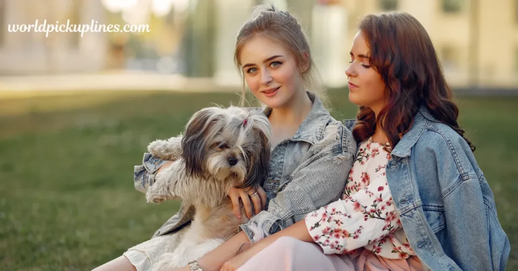 Two young women sitting outside on the grass in denim jackets, holding a small fluffy Shih Tzu dog, with "worldpickuplines.com" overlayed in the top left corner.