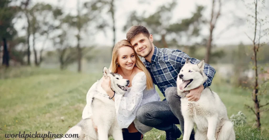 Smiling couple posing outdoors while hugging two Siberian Huskies, with "worldpickuplines.com" in the lower left corner.