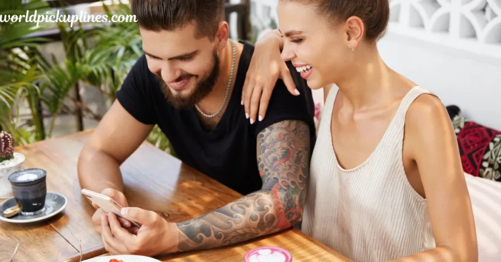 A man with a tattooed arm and a woman looking together at a smartphone screen at an outdoor café table.